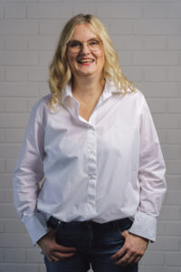 Frau mit blonden, langen Haaren in Jeans und weißer Bluse